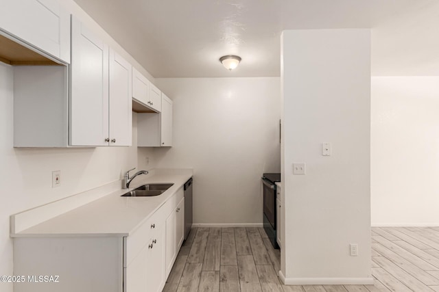 kitchen with a sink, black electric range oven, light wood-type flooring, white cabinets, and dishwasher