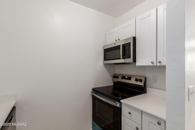 kitchen featuring stainless steel appliances, white cabinets, and light countertops