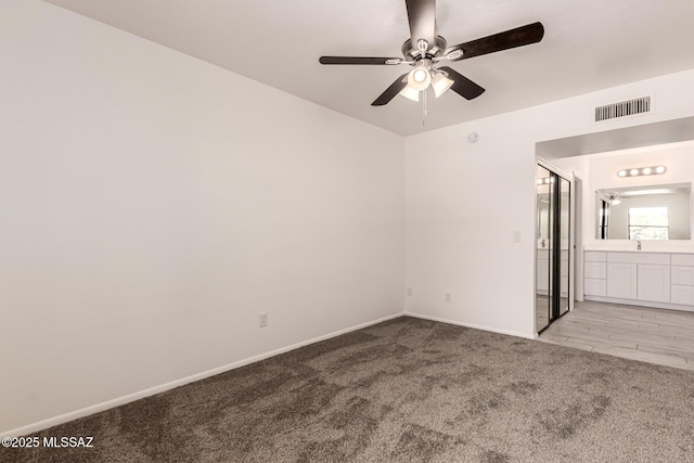 unfurnished bedroom featuring light carpet, baseboards, connected bathroom, and ceiling fan