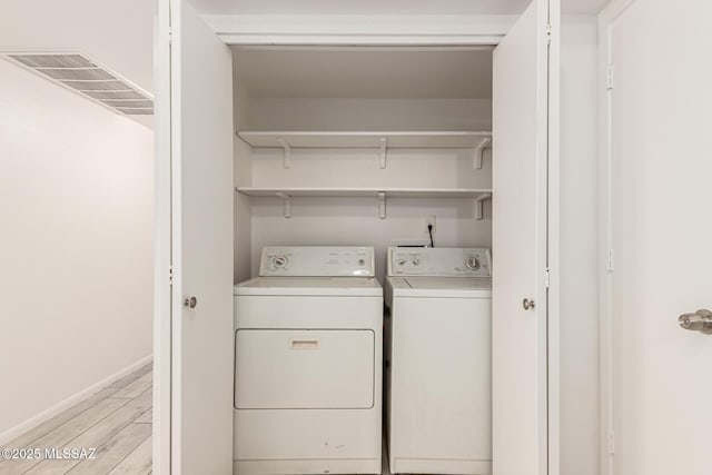 washroom with washer and dryer, light wood-style floors, and baseboards