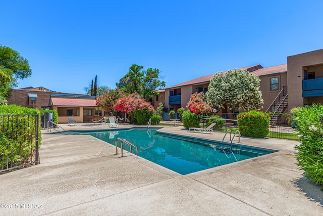 community pool with a patio area and fence