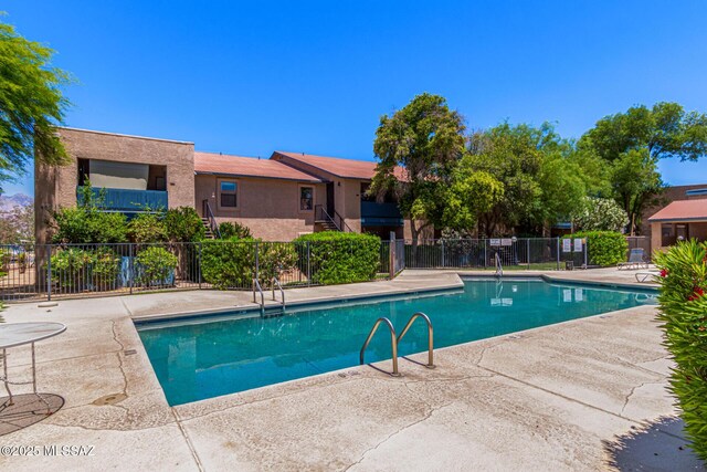 community pool with fence and a patio area