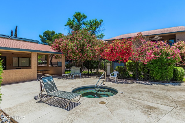 view of patio / terrace featuring a community hot tub and fence