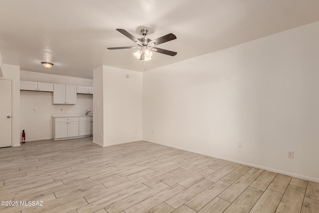 unfurnished living room with ceiling fan, light wood-style floors, and baseboards