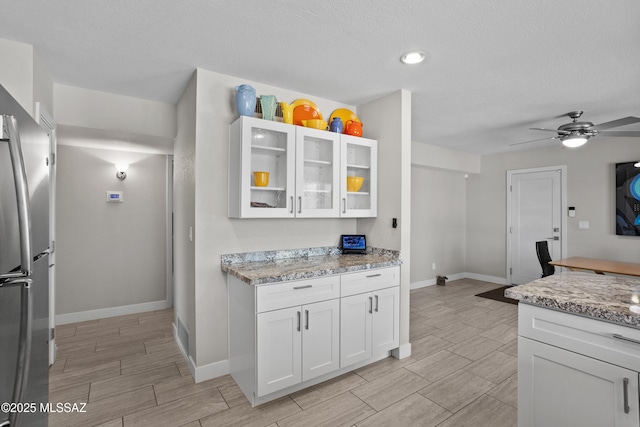 2282 W Rapallo Way, Tucson, AZ 85741 - kitchen featuring freestanding refrigerator, white cabinets, light stone countertops, wood finish floors, and a textured ceiling