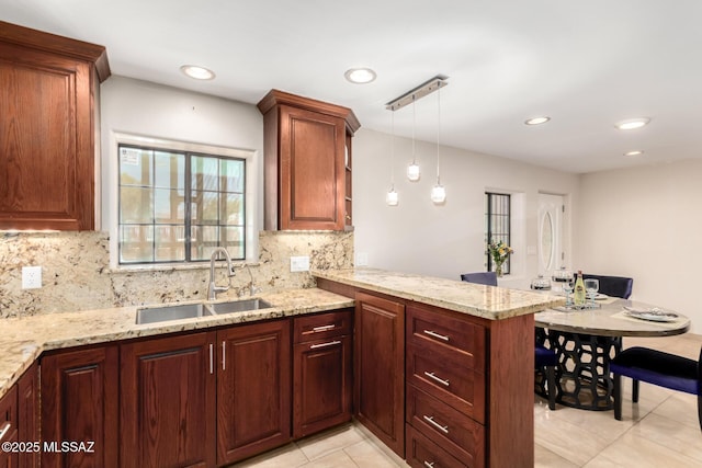 kitchen featuring a sink, a peninsula, tasteful backsplash, light stone countertops, and light tile patterned flooring