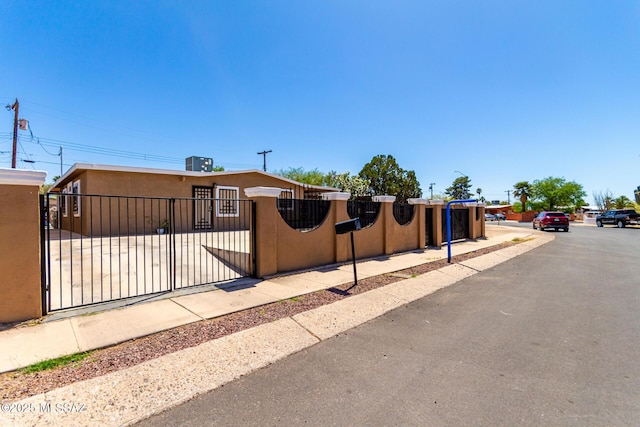 view of front facade with stucco siding, a fenced front yard, and a gate