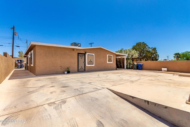 back of house featuring stucco siding, fence, and central AC