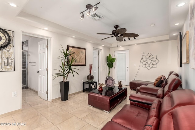 living area with a raised ceiling, recessed lighting, ceiling fan, and baseboards