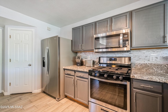 14570 S Sumac Dr, Sahuarita, AZ 85629 - kitchen featuring appliances with stainless steel finishes, light wood finished floors, backsplash, light stone countertops, and gray cabinets