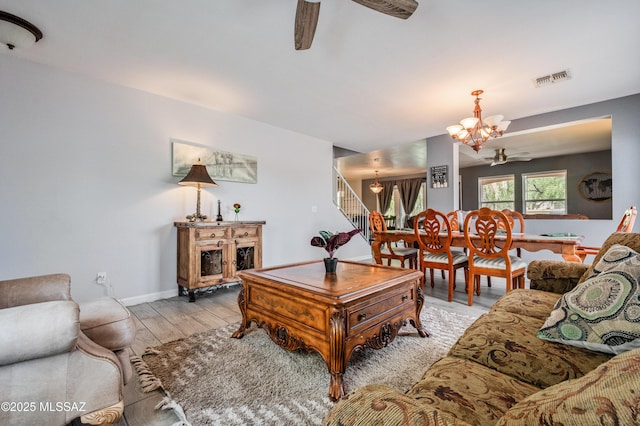 14570 S Sumac Dr, Sahuarita, AZ 85629 - living room featuring a chandelier, ceiling fan, light wood finished floors, stairway, and baseboards