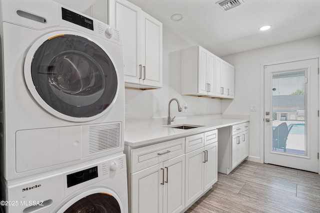 3454 E Calle Del Prado, Tucson, AZ 85716 - laundry area featuring stacked washer and clothes dryer, recessed lighting, cabinet space, light wood-type flooring, and baseboards
