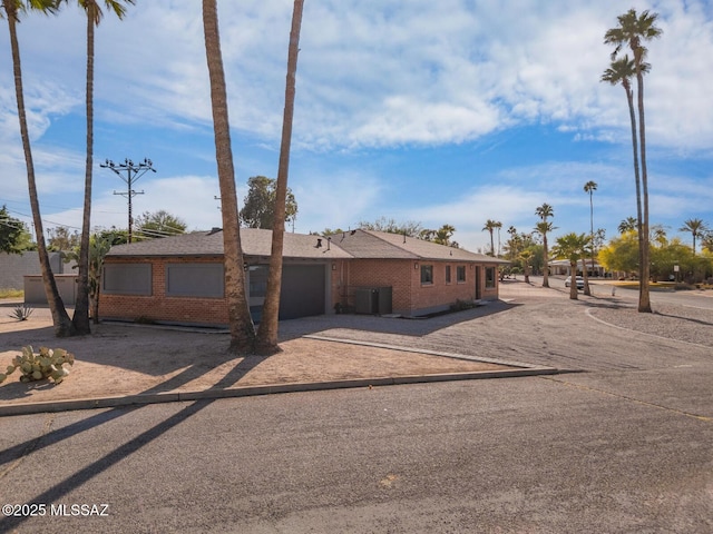 3454 E Calle Del Prado, Tucson, AZ 85716 - ranch-style house featuring dirt driveway, brick siding, a garage, and cooling unit
