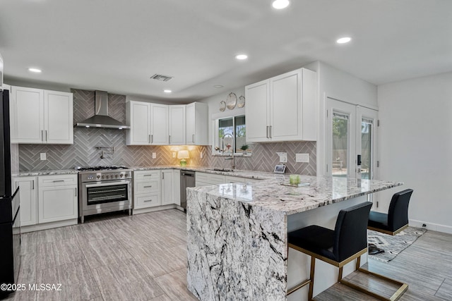 3454 E Calle Del Prado, Tucson, AZ 85716 - kitchen featuring stainless steel appliances, wall chimney range hood, a sink, tasteful backsplash, and light stone countertops