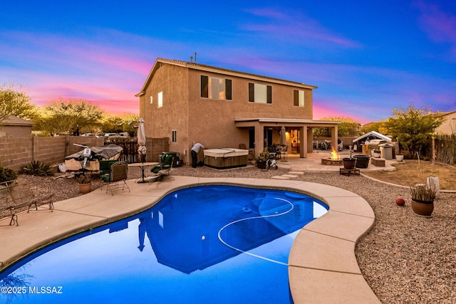 14234 E Placita Niebla, Tucson, AZ 85747 - pool at dusk with an outdoor fire pit, a hot tub, a patio, and a fenced backyard
