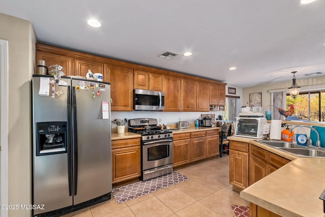 14234 E Placita Niebla, Tucson, AZ 85747 - kitchen with stainless steel appliances, a sink, brown cabinets, light tile patterned floors, and recessed lighting