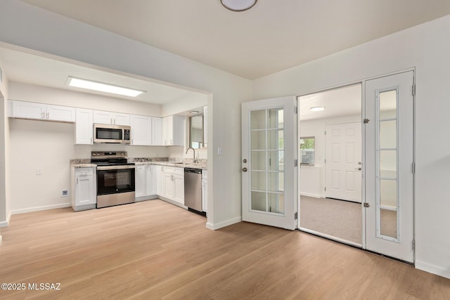1540 N Calle Valencia, Oracle, AZ 85623 - kitchen with appliances with stainless steel finishes, white cabinets, light wood finished floors, a sink, and light stone countertops