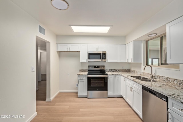 1540 N Calle Valencia, Oracle, AZ 85623 - kitchen featuring stainless steel appliances, a sink, light wood finished floors, light stone countertops, and white cabinets
