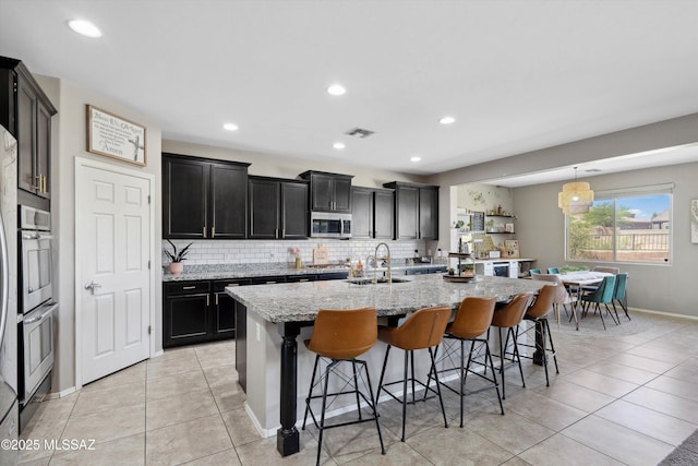 9693 N Melandra Way, Marana, AZ 85653 - kitchen with a sink, stainless steel appliances, dark cabinets, backsplash, and a kitchen island with sink