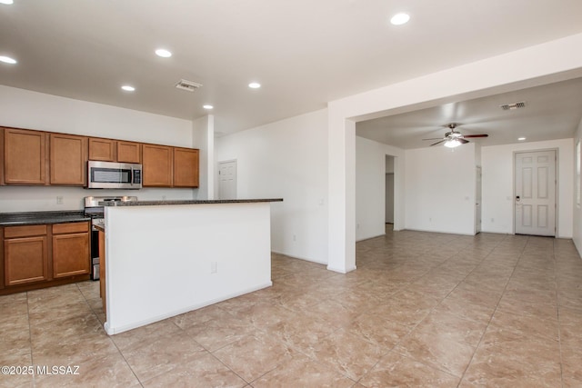6837 W Leeward Cove Way, Tucson, AZ 85757 - kitchen with appliances with stainless steel finishes, brown cabinets, dark countertops, recessed lighting, and a ceiling fan