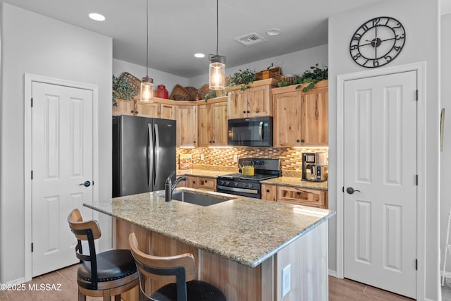 2108 W Moon Milk St, Benson, AZ 85602 - kitchen with black microwave, stainless steel range with gas stovetop, freestanding refrigerator, light wood-style floors, and a sink