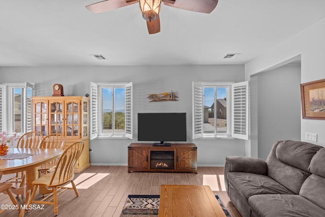 2108 W Moon Milk St, Benson, AZ 85602 - living area featuring light wood finished floors, healthy amount of natural light, a ceiling fan, and baseboards