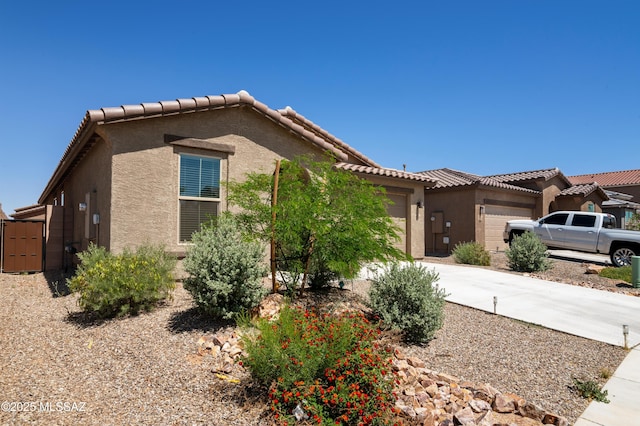 view of front of property with an attached garage, stucco siding, driveway, and a tile roof