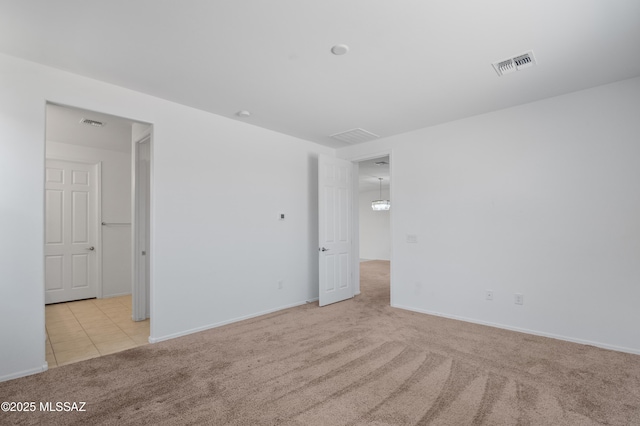 carpeted spare room featuring baseboards and tile patterned flooring