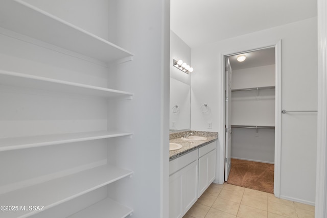 bathroom featuring double vanity, tile patterned flooring, and a walk in closet