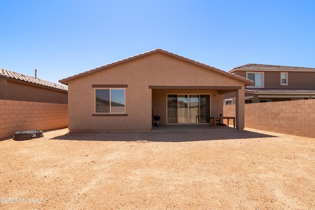 rear view of property with fence, stucco siding, and a patio