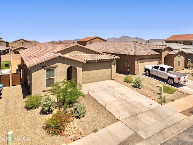 view of front of home with a garage, stucco siding, a tile roof, driveway, and a mountain view