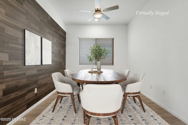 12513 Denton Way, Marana, AZ 85653 - dining area featuring an accent wall, a ceiling fan, baseboards, wood finished floors, and wood walls