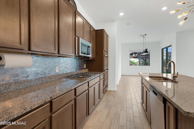 12513 Denton Way, Marana, AZ 85653 - kitchen with appliances with stainless steel finishes, a sink, backsplash, a chandelier, and dark stone counters