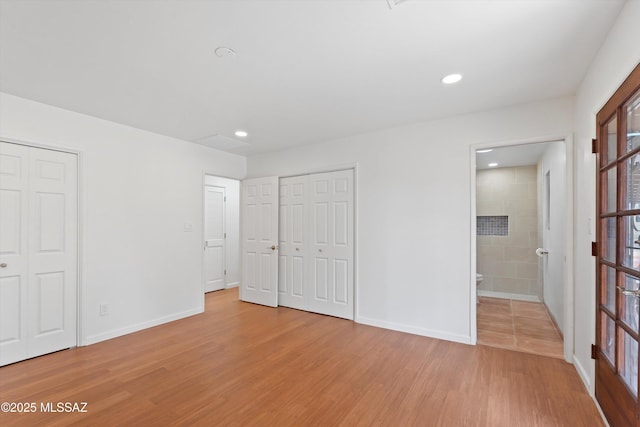 1241 W Cananea Cir, Tucson, AZ 85704 - unfurnished bedroom with light wood finished floors, baseboards, ensuite bath, recessed lighting, and multiple closets