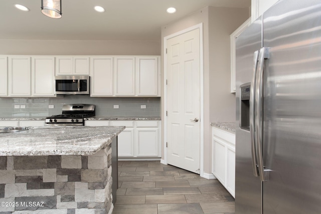 8040 N Desert Gum Dr, Tucson, AZ 85741 - kitchen featuring appliances with stainless steel finishes, recessed lighting, white cabinets, tasteful backsplash, and light stone countertops