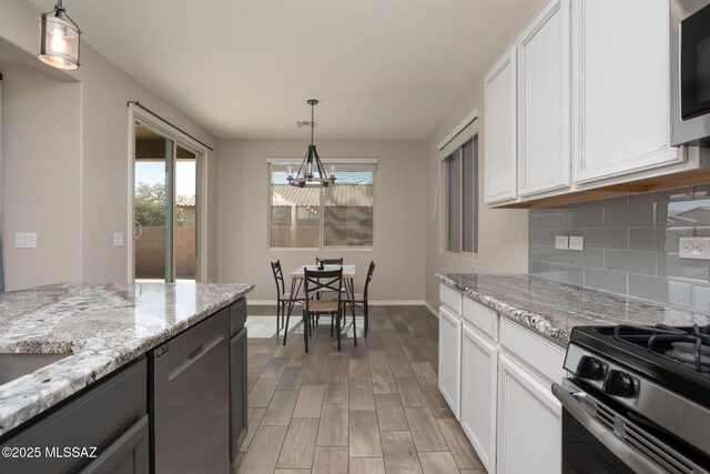 8040 N Desert Gum Dr, Tucson, AZ 85741 - kitchen featuring a chandelier, appliances with stainless steel finishes, decorative backsplash, light wood-style flooring, and baseboards
