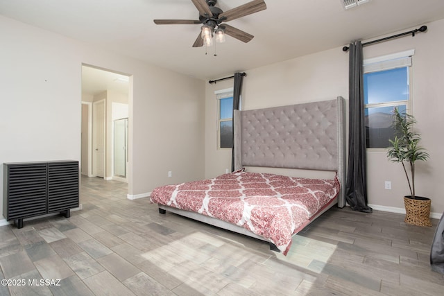 8040 N Desert Gum Dr, Tucson, AZ 85741 - bedroom featuring a barn door, light wood-style flooring, baseboards, and a ceiling fan