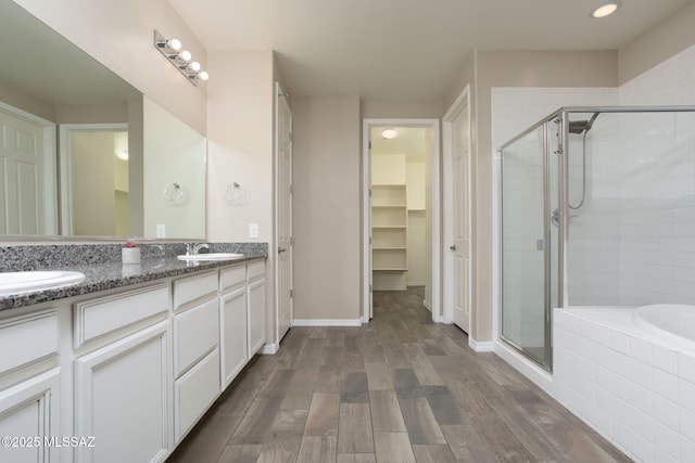 8040 N Desert Gum Dr, Tucson, AZ 85741 - bathroom featuring a shower stall, a walk in closet, double vanity, a relaxing tiled tub, and wood finished floors