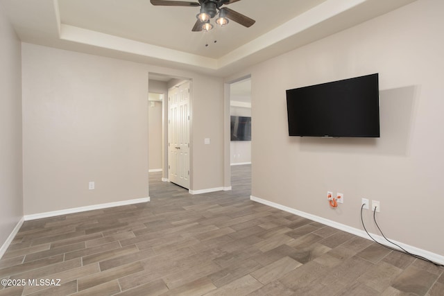 8040 N Desert Gum Dr, Tucson, AZ 85741 - unfurnished living room with a ceiling fan, wood finished floors, a tray ceiling, and baseboards