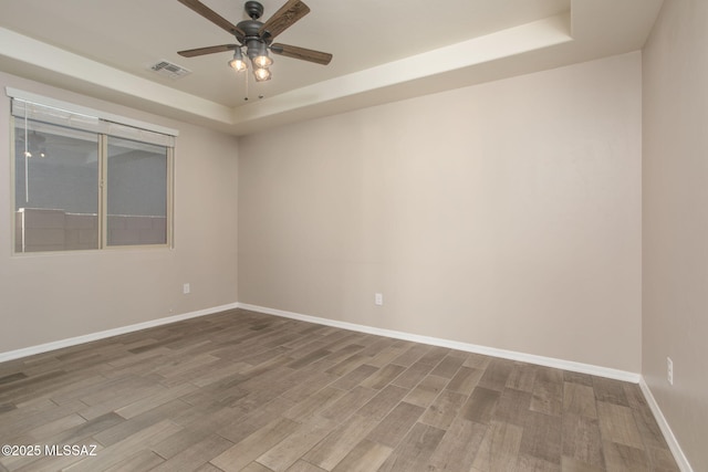8040 N Desert Gum Dr, Tucson, AZ 85741 - spare room featuring a tray ceiling, wood finished floors, ceiling fan, and baseboards