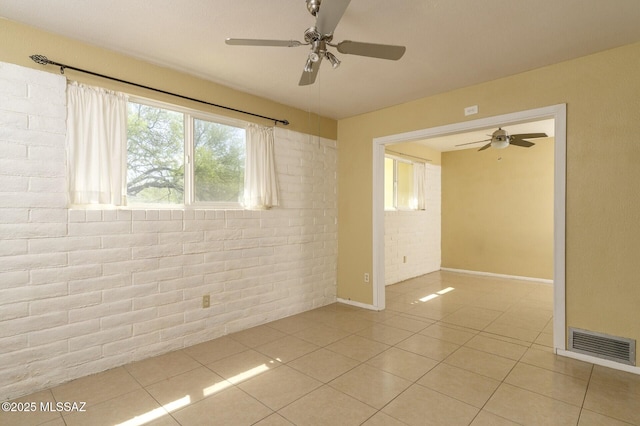 3600 N Hash Knife Cir, Tucson, AZ 85749 - empty room with ceiling fan, brick wall, plenty of natural light, light tile patterned floors, and baseboards
