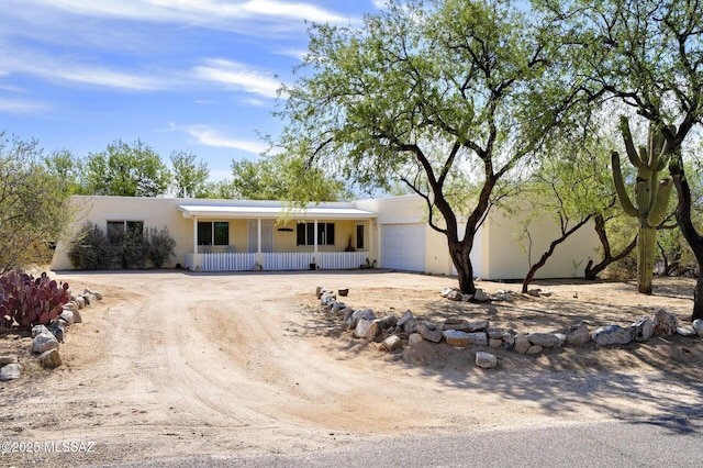 3600 N Hash Knife Cir, Tucson, AZ 85749 - view of front facade with an attached garage, a porch, dirt driveway, and stucco siding