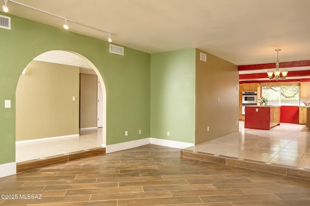 3600 N Hash Knife Cir, Tucson, AZ 85749 - spare room featuring track lighting, a chandelier, arched walkways, and wood tiled floors