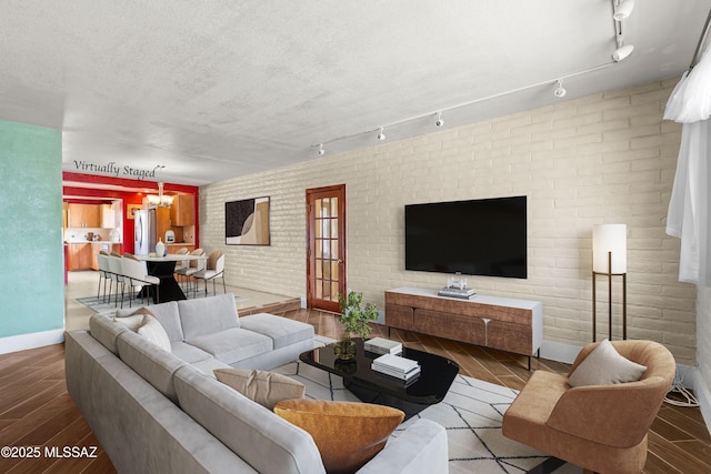 3600 N Hash Knife Cir, Tucson, AZ 85749 - living room with wood finished floors, a chandelier, baseboards, brick wall, and rail lighting