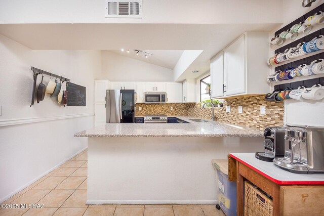 2804 W Camino Ebano, Tucson, AZ 85742 - kitchen featuring stainless steel appliances, a peninsula, lofted ceiling, tasteful backsplash, and white cabinets