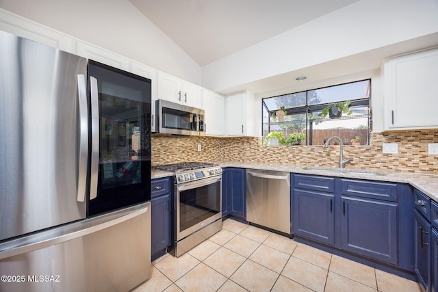 2804 W Camino Ebano, Tucson, AZ 85742 - kitchen featuring stainless steel appliances, blue cabinets, vaulted ceiling, a sink, and backsplash