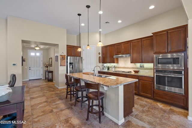 59962 E Arroyo Grande Dr, Oracle, AZ 85623 - kitchen with stainless steel appliances, under cabinet range hood, tasteful backsplash, a sink, and a breakfast bar