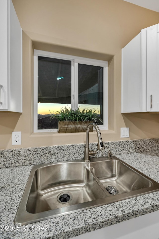 174 Via Casa, Rio Rico, AZ 85648 - kitchen view of a sink, white cabinetry, and light stone counters