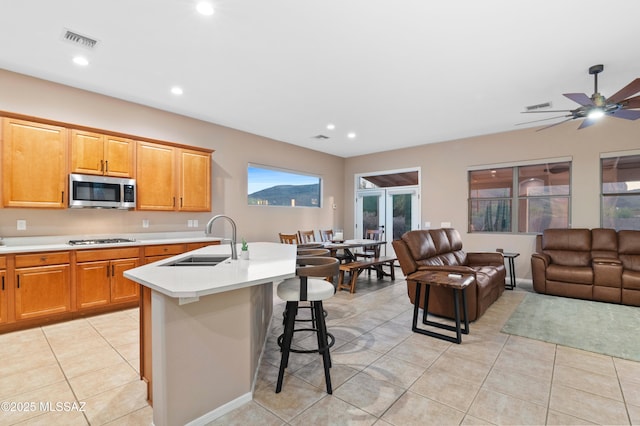 8183 N Sombrero Point Dr, Tucson, AZ 85743 - kitchen featuring stainless steel microwave, open floor plan, light countertops, a kitchen island with sink, and light tile patterned flooring