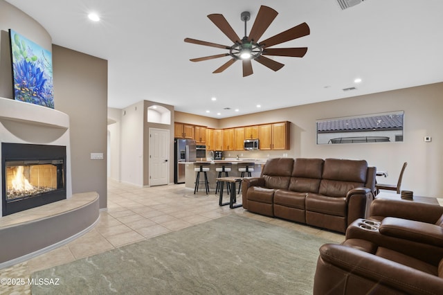 8183 N Sombrero Point Dr, Tucson, AZ 85743 - living area with light tile patterned floors, a ceiling fan, recessed lighting, and a warm lit fireplace